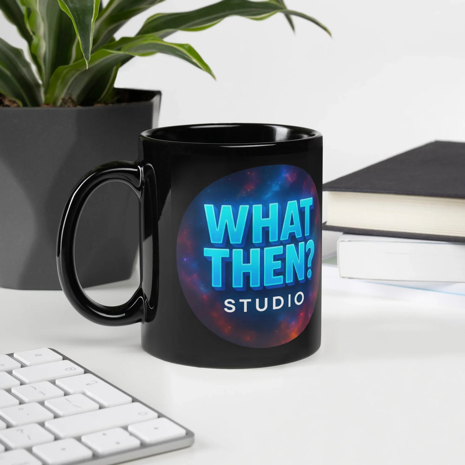 Black glossy What Then Studio mug on desk with plant, keyboard, and books