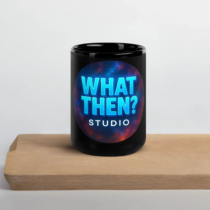 Black glossy mug with 'What Then? Studio' logo on a wooden board