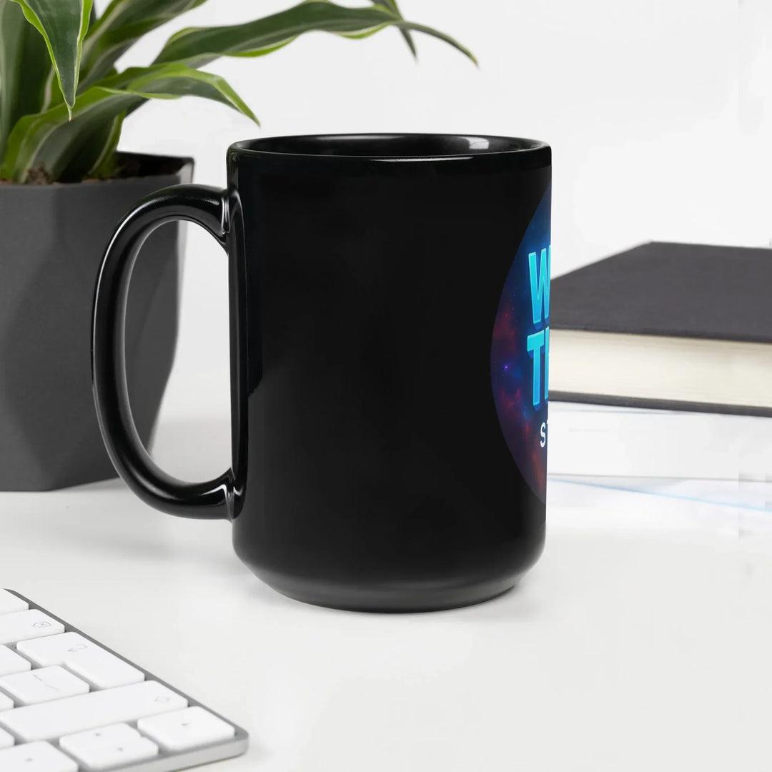 Black glossy What Then Studio mug on white desk with plant, book, and keyboard