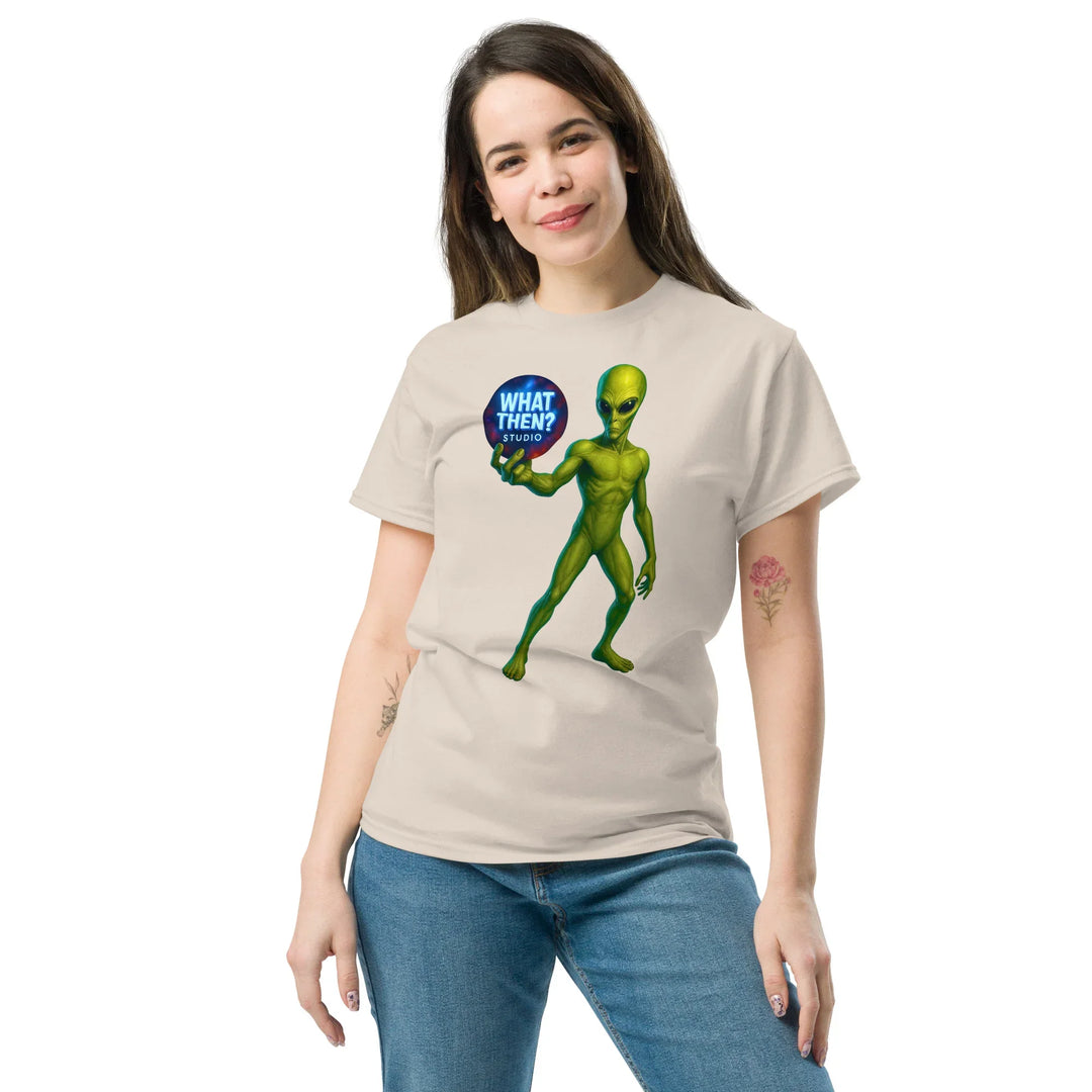 Woman wears beige t-shirt with green alien holding 'What Then? Studio' logo, What Then Studio merch