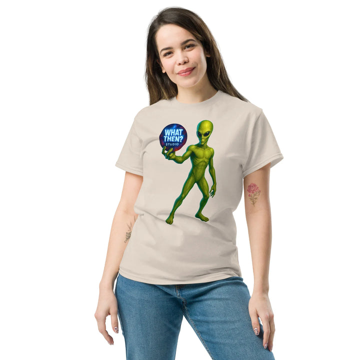 Woman wears beige t-shirt with green alien holding 'What Then? Studio' logo, What Then Studio merch