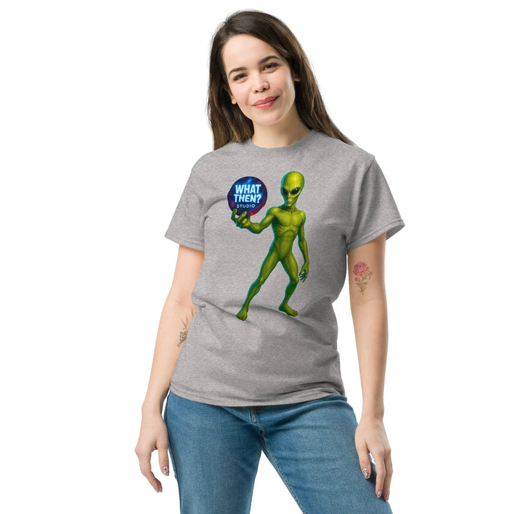 Woman wearing grey What Then Studio t-shirt with green alien graphic and blue logo text.