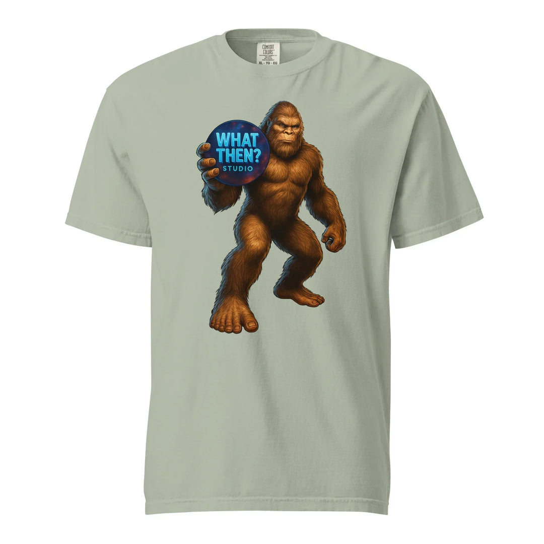 Unisex heavyweight t-shirt with Bigfoot holding 'What Then? Studio' logo graphic on front.