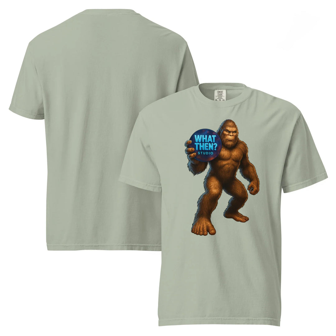 Unisex heavyweight t-shirt in bay color with Bigfoot holding 'What Then? Studio' logo on front