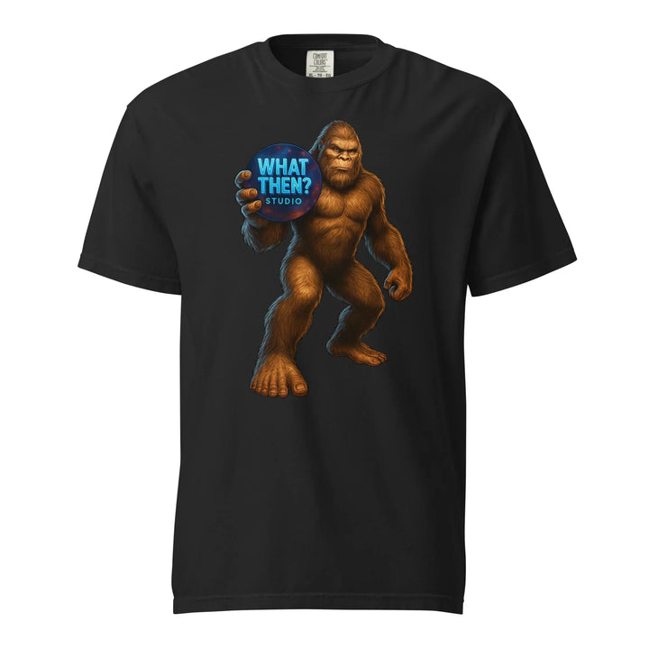 Black heavyweight unisex t-shirt featuring Bigfoot holding a What Then? Studio logo sphere.