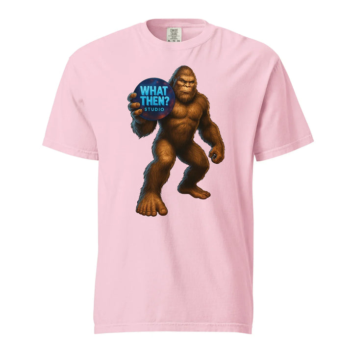 Pink unisex heavyweight t-shirt with Bigfoot holding a 'What Then? Studio' sign graphic