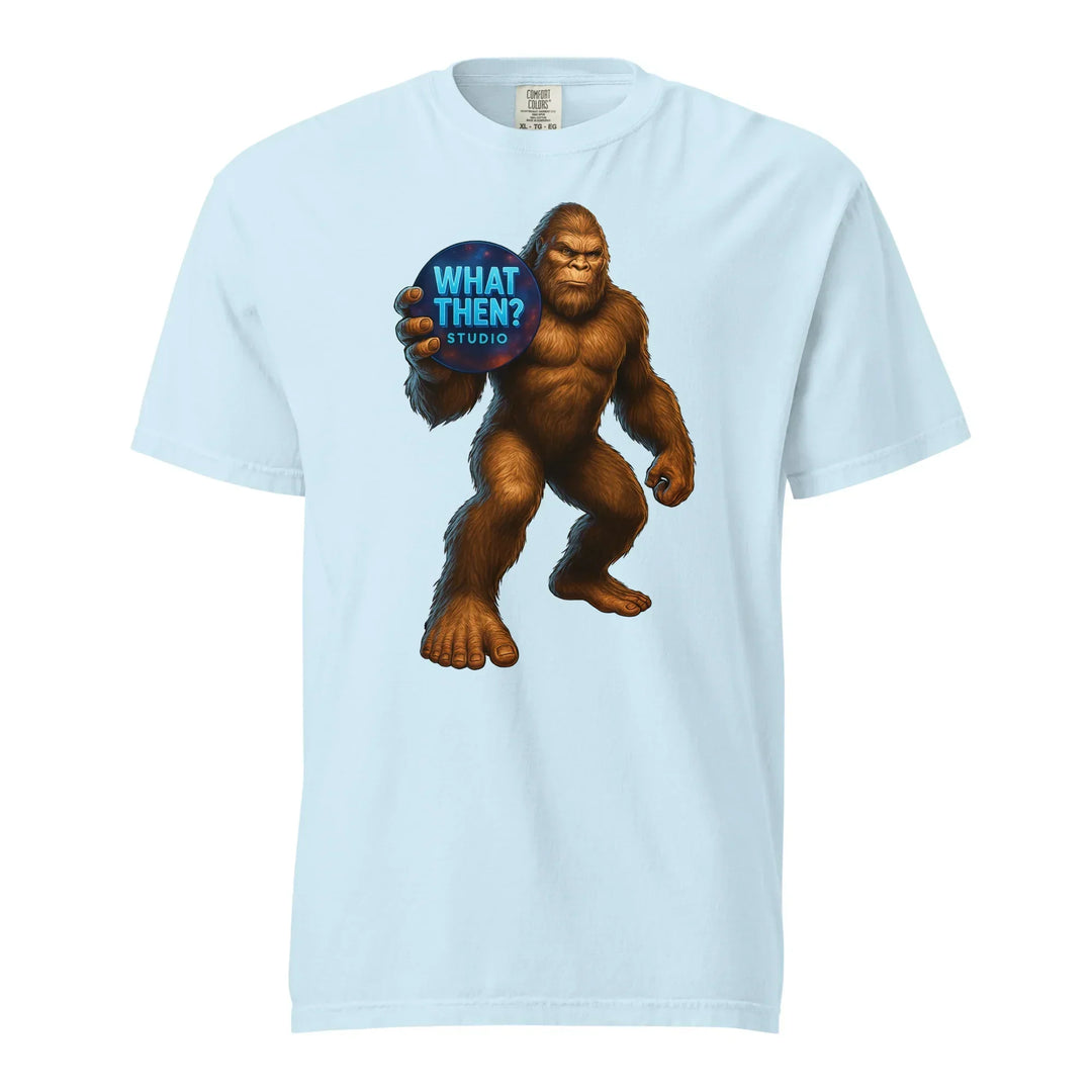 Light blue unisex t-shirt with Bigfoot holding 'What Then? Studio' logo graphic.